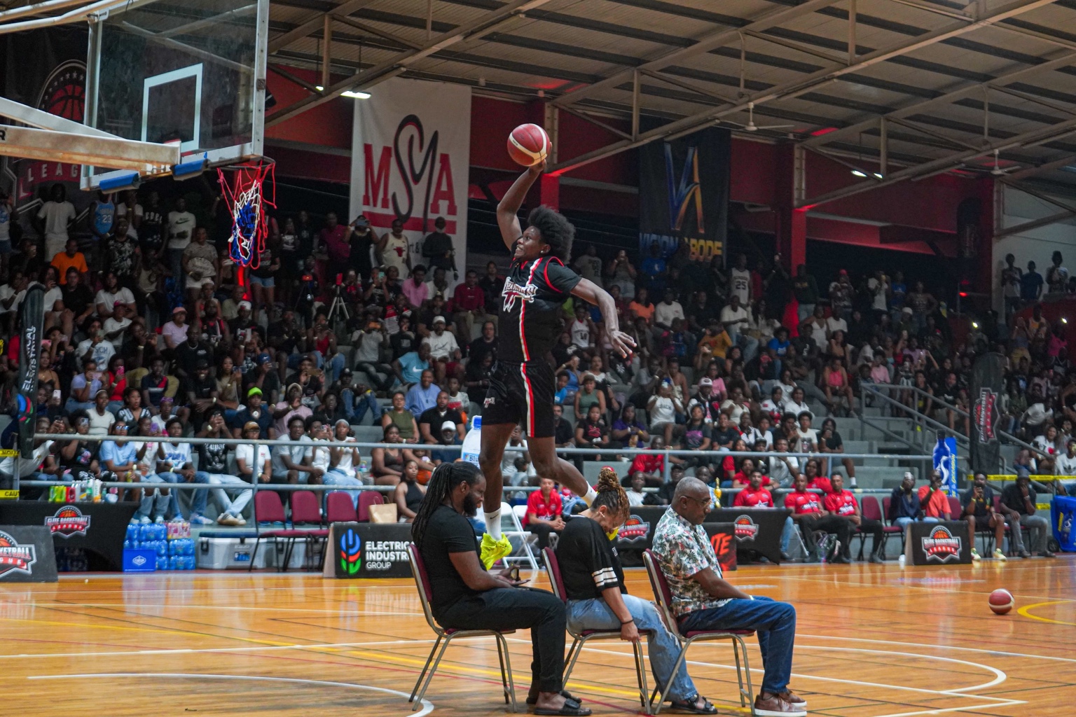 Michael McCarthy attempts a dunk over three seated patrons during the All-Star dunk final.